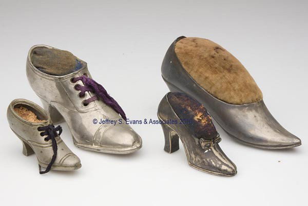 VARIOUS METALS FIGURAL PIN CUSHIONS, LOT OF FOUR: VARIOUS METALS FIGURAL PIN CUSHIONS, LOT OF FOUR, each depicting a silver-plated high-heel shoe, consisting of a Jennings Brothers example, embossed on sole "1423" with maker's initials; two examples 