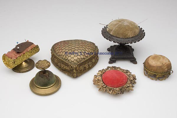 VARIOUS MATERIALS PIN CUSHIONS, LOT OF SIX: VARIOUS MATERIALS PIN CUSHIONS, LOT OF SIX, five metal examples consisting of a cast-iron example with mushroom-form top, a brass example, and three with brass finishes, including one with a hinged to