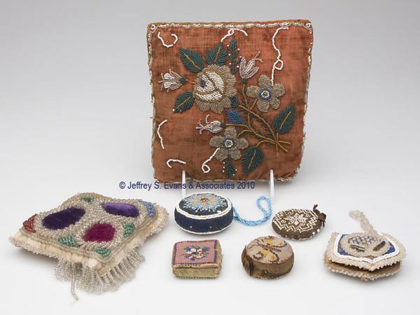 HANDMADE BEADED PIN CUSHIONS, LOT OF SEVEN: HANDMADE BEADED PIN CUSHIONS, LOT OF SEVEN, various floral and geometrical patterns, consisting of a square and a heart pillow; three disk-form examples including one with a handle; and two booklet-fo