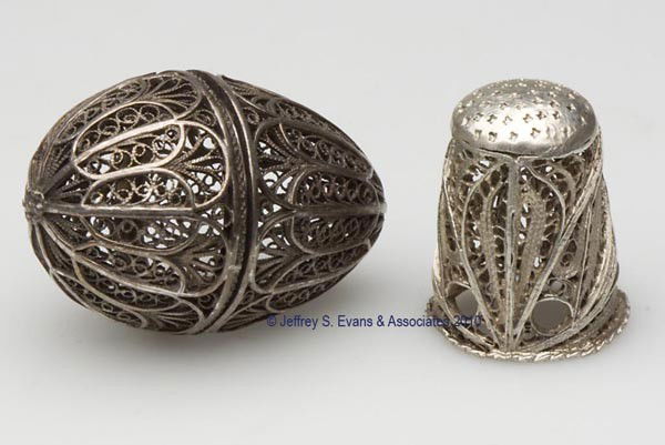 SILVER-LIKE FILIGREE THIMBLE CASE AND THIMBLE: SILVER-LIKE FILIGREE THIMBLE CASE AND THIMBLE, egg form with hinged lid, scroll and feather pattern. Late 19th/early 20th century. 1 5/8" h, 1 1/8" dia overall. Provenance: Collection of the late Hild