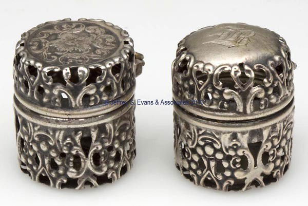 WEBSTER CO. STERLING SILVER PIERCED THIMBLE CASES,: WEBSTER CO. STERLING SILVER PIERCED THIMBLE CASES, LOT OF TWO, each with heavily embossed scroll pattern, one example with a floral embossed top and a thimble post, other with an unpatterned top and m
