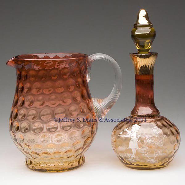 CONTEMPORARY AMBERINA INVERTED THUMBPRINT ARTICLES: CONTEMPORARY AMBERINA INVERTED THUMBPRINT ARTICLES, LOT OF TWO, comprising a pitcher with colorless reeded applied handle, and a decanter with so-called Mary Gregory and gilt decoration. Mid 20th cent