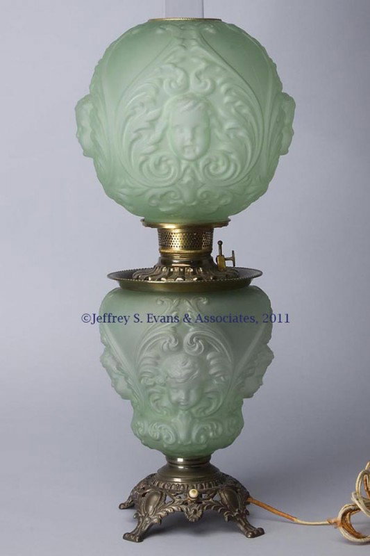 SATIN FINISH PARLOR LAMP: SATIN FINISH PARLOR LAMP, green, embossed with cherub faces and scrolls, matching patterned ball shade, cast metal base embossed "300" to underside, font with a metal lining and brass E. Miller & Co d