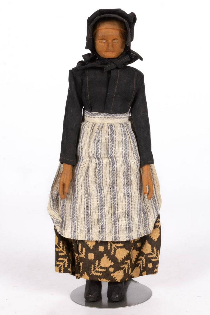 APPALACHIAN / SOUTHERN CARVED WOODEN ELDERLY WOMAN DOLL: APPALACHIAN / SOUTHERN CARVED WOODEN ELDERLY WOMAN DOLL, fitted in period attire, including printed skirt, blue ticking-style apron, and bonnet. Original dry natural surface. Circa 1920. 10 1/4" HOA. 