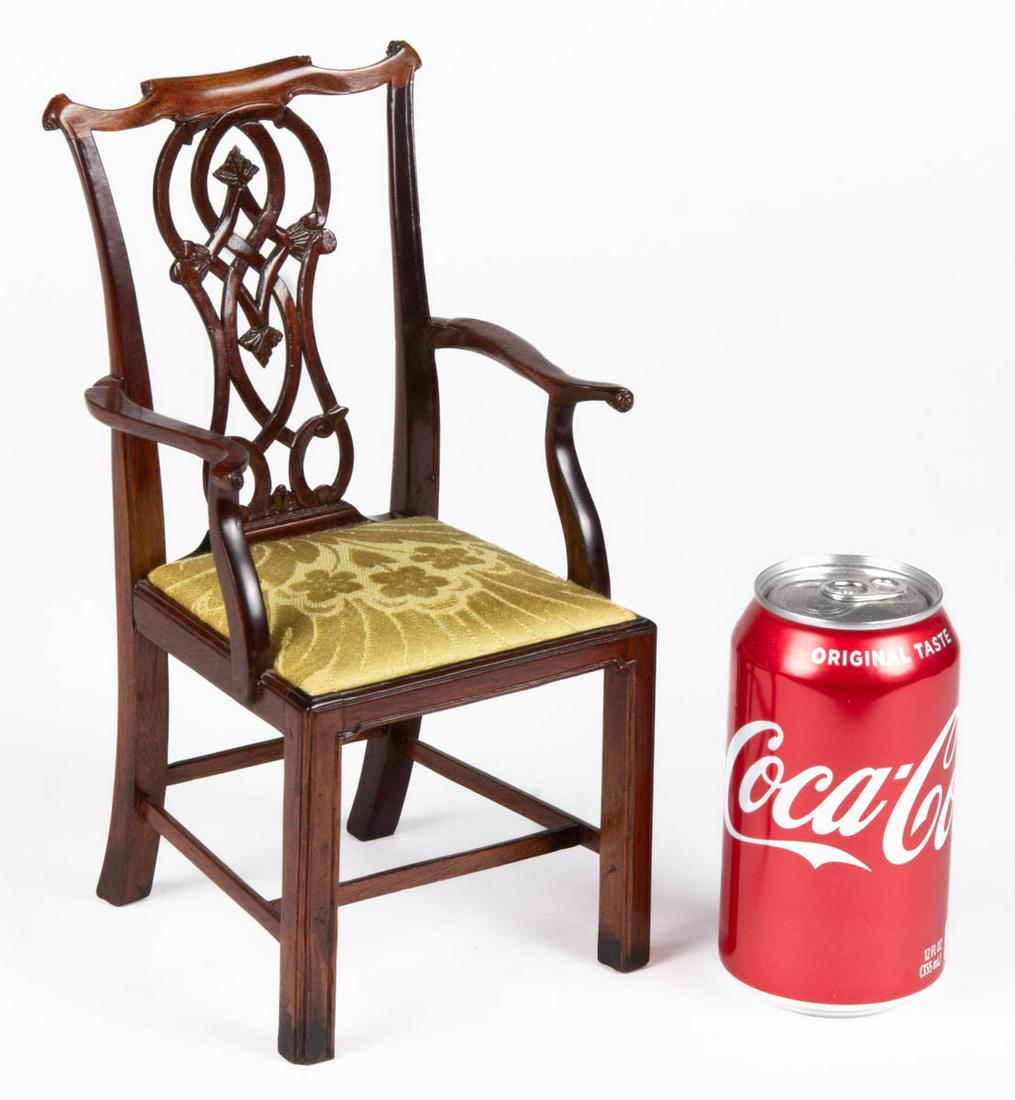 CHIPPENDALE CARVED MAHOGANY DOLL ARMCHAIR: CHIPPENDALE CARVED MAHOGANY DOLL ARMCHAIR, boldly shaped crest above a pierced, intertwined splat and shaped arms attached with wooden pens, trapezoidal slip seat, raised on square, molded legs joined