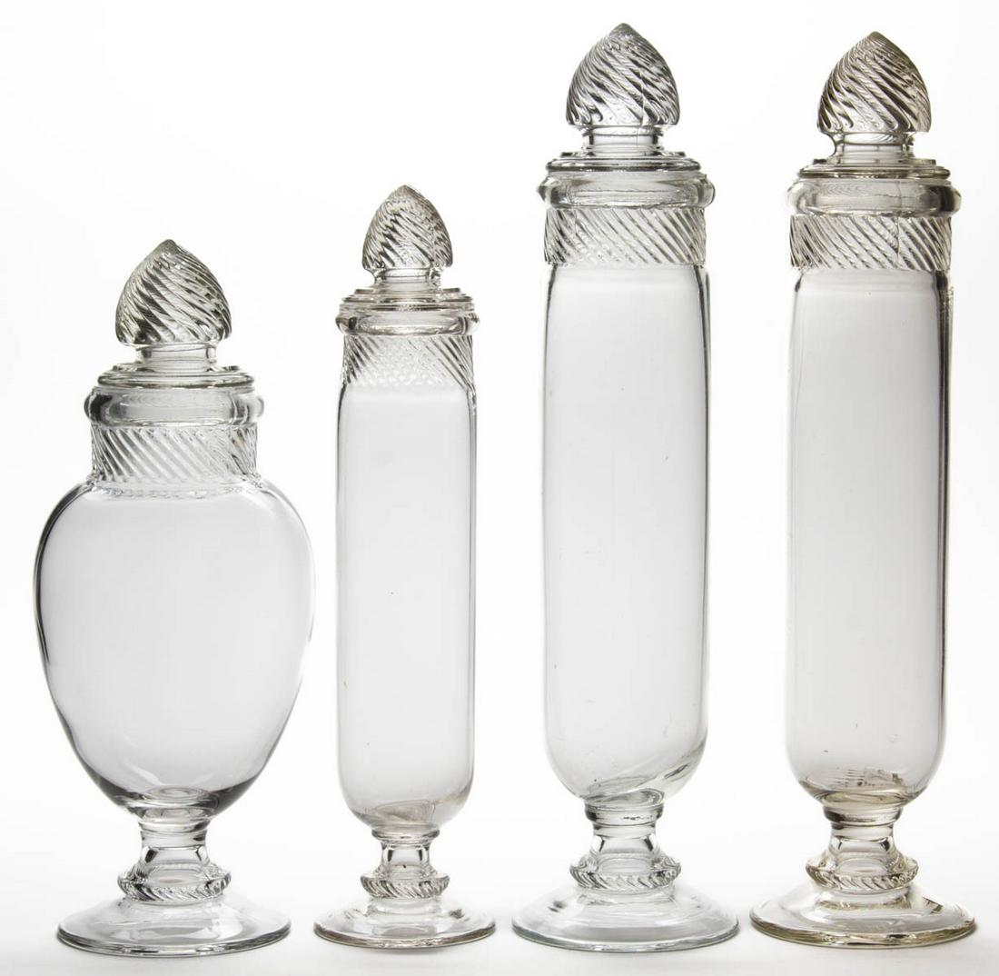 COLUMBIA (OMN) APOTHECARY / SAMPLE JARS, LOT OF FOUR: COLUMBIA (OMN) APOTHECARY / SAMPLE JARS, LOT OF FOUR, colorless, comprising three tall cylindrical form and one bulged form, each having a matching lid. U.S. Glass Co. Circa 1900. 15" to 19 1/2" HOA. 