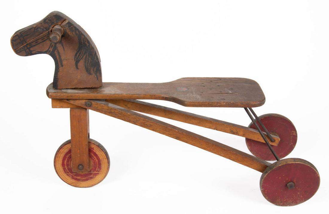 MORTON E. CONVERSE WOODEN HORSE TRICYCLE RIDING TOY: MORTON E. CONVERSE WOODEN HORSE TRICYCLE RIDING TOY, having a horse head with handles for steering, mounted on a plank seat with "Converse" mark, on three painted wood wheels. Old surface. Morton E. C