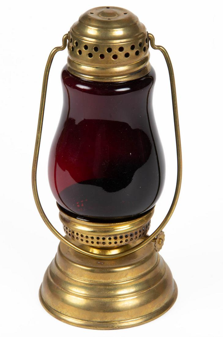 BRASS SKATER'S LANTERN: BRASS SKATER'S LANTERN, very deep dark ruby/red globe, removable perforated cap with bail handle, stepped conical-form font. Fitted with a period burner. Early 20th century. 11 1/4" H to top of handle