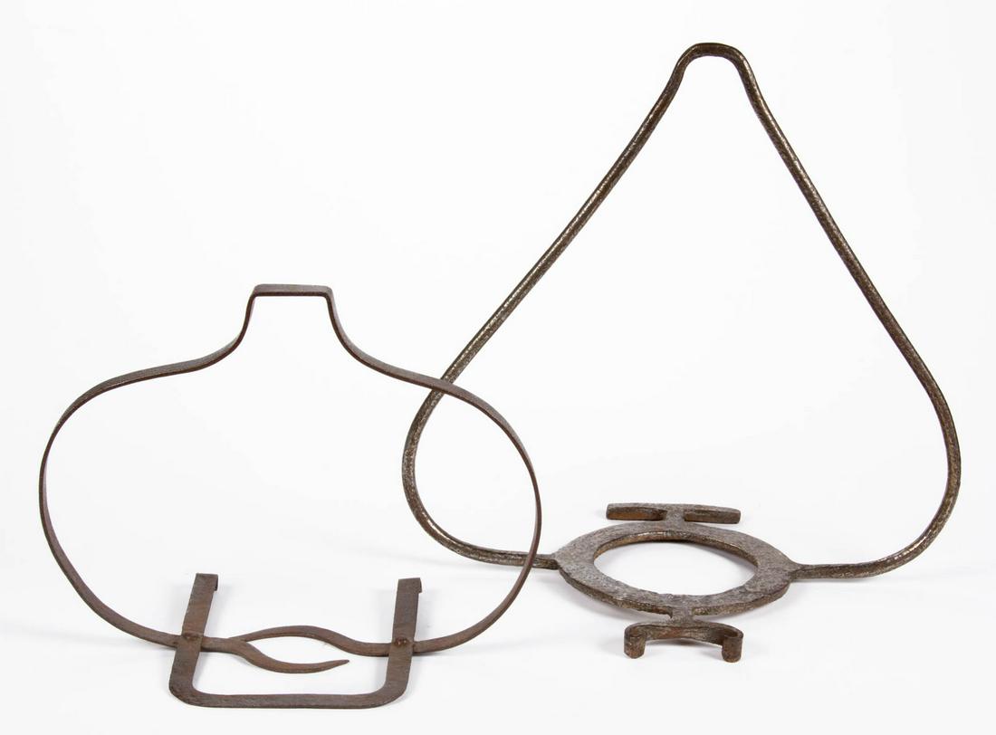 ASSORTED WROUGHT-IRON HEARTH HANGING POT HOLDERS /: ASSORTED WROUGHT-IRON HEARTH HANGING POT HOLDERS / TRIVETS, LOT OF TWO, each with arched arms supporting a stylized holder, including one with flat arms and a rectangular-form with scroll holder and r