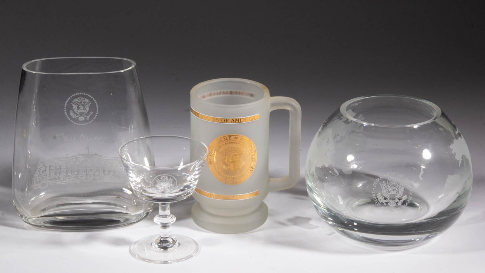 ASSORTED HISTORICAL / PRESIDENTIAL GLASS ARTICLES, LOT: ASSORTED HISTORICAL / PRESIDENTIAL GLASS ARTICLES, LOT OF FOUR, colorless, comprising a "DEPARTMENT OF STATE" globe vase with seal, a "LENOX" champagne with an etched presidential seal, a frosted colo