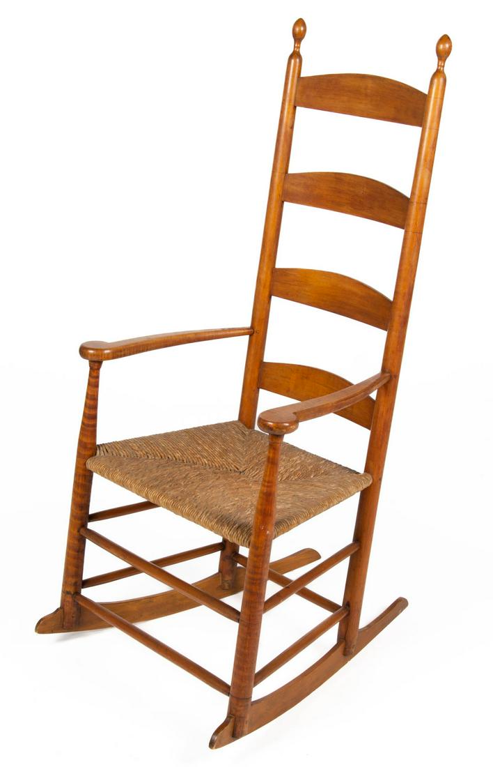 SHAKER TIGER MAPLE LADDERBACK ROCKING CHAIR: SHAKER TIGER MAPLE LADDERBACK ROCKING CHAIR, featuring four-slat back, later rush seat. Retaining an old surface with warm color. 19th century. 44 1/2" HOA, 14 1/2" x 20" seat. Provenance: Part Two - 