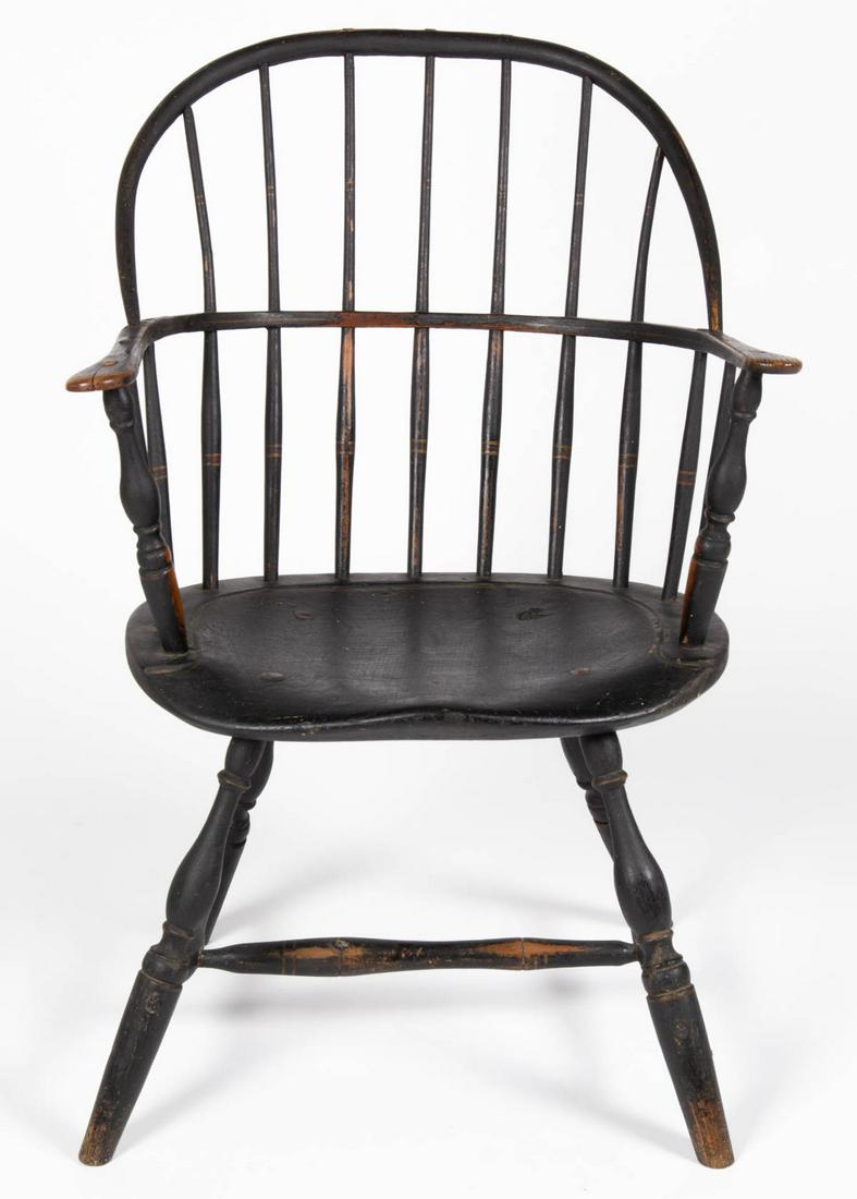 AMERICAN COUNTRY SACK-BACK WINDSOR ARMCHAIR: AMERICAN COUNTRY SACK-BACK WINDSOR ARMCHAIR, bowed crest rail above seven spindles and shaped arms, shaped seat, raised on splayed turned legs, joined by a turned H-form stretcher. Retains an old blac
