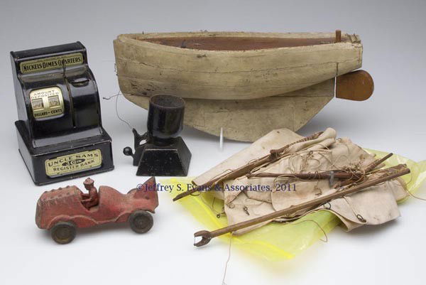 FOUR ASSORTED VINTAGE TOYS: FOUR ASSORTED VINTAGE TOYS, comprising a cast-iron racer with solid iron wheels, a wooden sailboat with masts and sails, a tin Uncle Sam's Register Bank, and a cast-iron howitzer. First half 20th cent