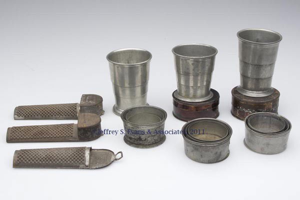 ASSORTED METAL DOMESTIC ARTICLES, LOT OF NINE: ASSORTED METAL DOMESTIC ARTICLES, LOT OF NINE, comprising six pewter collapsible tumblers, two with original case and two signed for Philadelphia makers, along with three tin nutmeg graters. 19th cent