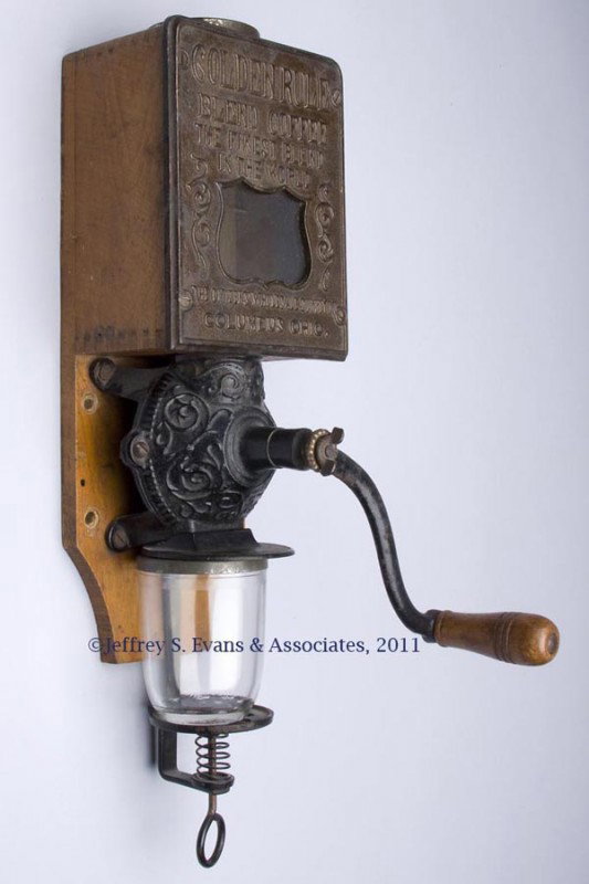 GOLDEN RULE WALL COFFEE GRINDER: GOLDEN RULE WALL COFFEE GRINDER, cast iron and wood, Columbus, Ohio, tin top cap and glass jar of unknown association, original surfaces. Late 19th/early 20th century. 17 1/2" H. Provenance: From a Ne