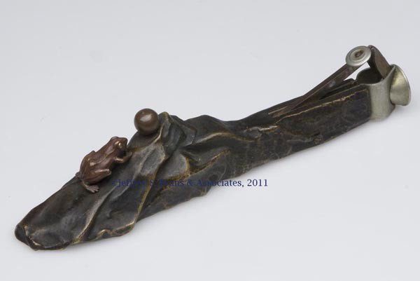 TWO-TONE BRONZE FIGURAL CIGAR CUTTER: TWO-TONE BRONZE FIGURAL CIGAR CUTTER, depicting a frog approaching an orb on a rocky ground. Probably Asian. Late 19th/early 20th century. 6 1/8" L. Provenance: From a New York estate.