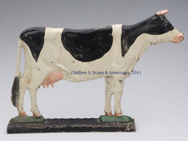 HOLSTEIN COW CAST-IRON DOORSTOP: HOLSTEIN COW CAST-IRON DOORSTOP, solid double-sided figure, standing on a narrow, separately-cast base with notched upper edges, original naturalistic paint. First half 20th century. 8 3/4" H, 13" L. 
