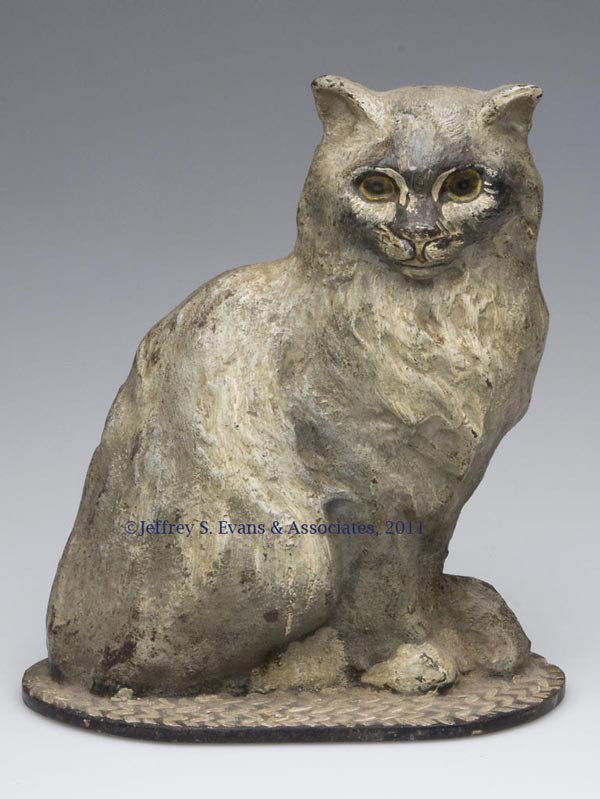 SITTING CAT ON OVAL RUG CAST-IRON DOORSTOP: SITTING CAT ON OVAL RUG CAST-IRON DOORSTOP, half figure, original paint. National Foundry. First half 20th century. 8 7/8" H, 7 5/8" W. Provenance: From a New York estate.