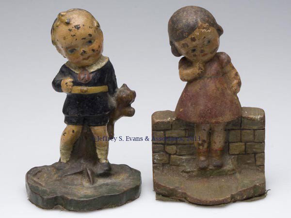 TWO ASSORTED CHILDREN FIGURAL CAST-IRON DOORSTOPS: TWO ASSORTED CHILDREN FIGURAL CAST-IRON DOORSTOPS, Boy Holding Teddy Bear and Girl By Brick Wall, each solid full figure, original paint. Albany Foundry. First half 20th century. 5 1/2" H. Provenance: