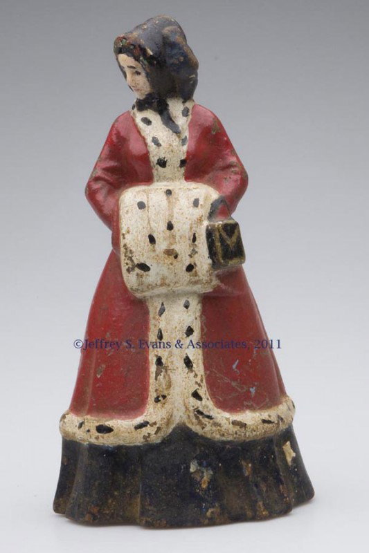 WOMAN WITH MUFF AND HATBOX CAST-IRON DOORSTOP: WOMAN WITH MUFF AND HATBOX CAST-IRON DOORSTOP, hollow full figure, original paint. Albany Foundry. First half 20th century. 9 1/2" H. Provenance: From a New York estate.