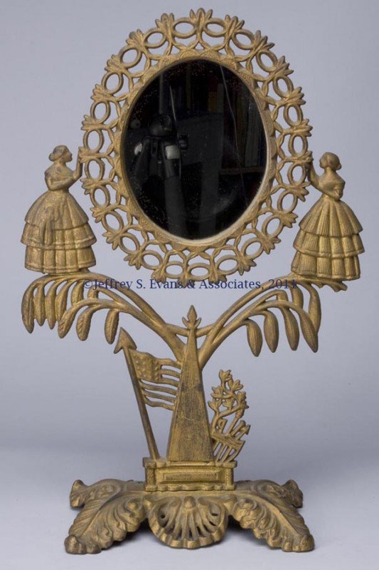 VICTORIAN CAST-IRON SWINGING SHAVING / TABLE TOP M: VICTORIAN CAST-IRON SWINGING SHAVING / TABLE TOP MIRROR, the mirror frame supported by two ladies standing on willow branches, above an American flag and shield, and an acanthus leaf and shell base, o