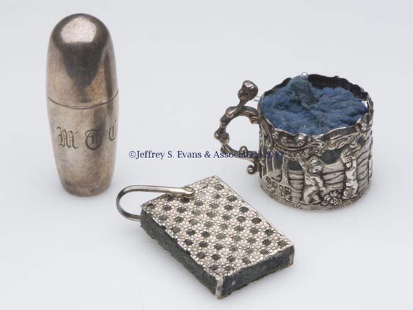 STERLING SILVER SEWING ARTICLES, LOT OF THREE: STERLING SILVER SEWING ARTICLES, LOT OF THREE, comprising a William Comyns & Sons Ltd possible pin cushion with cherub embossing; a book-form Nathan & Hayes pin cushion with chatelaine link; and a Her