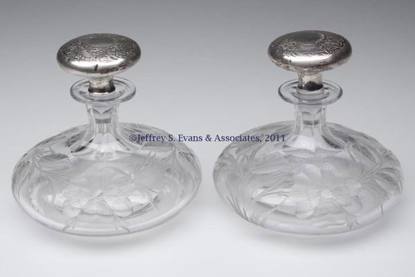 TUTHILL WILD ROSE INTAGLIO CUT GLASS PAIR OF COLOGN: TUTHILL WILD ROSE INTAGLIO CUT GLASS PAIR OF COLOGNE BOTTLES, with Gorham sterling silver-cased stoppers with "2860" within rectangle and date mark, signed. C. G. Tuthill & Co. 1911. 4 1/2" HOA, 5" DO