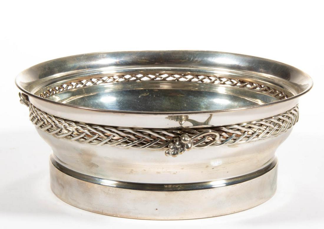CARTIER STERLING SILVER WINE COASTER: CARTIER STERLING SILVER WINE COASTER, round form with flared rim, woven design along shoulders with three applied grape motifs, having a wooden base. Bottom edge marked "CARTIER STERLING". Cartier, Pa