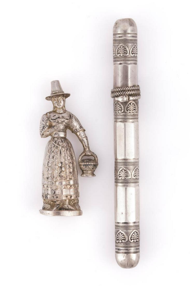 CONTINENTAL 0.800 SILVER SEWING NEEDLE CASES, LOT OF TWO: CONTINENTAL 0.800 SILVER SEWING NEEDLE CASES, LOT OF TWO, comprising a probably German 0.812 silver figural case of a woman in traditional dress wearing a hat and holding a basket of flowers, and a Du