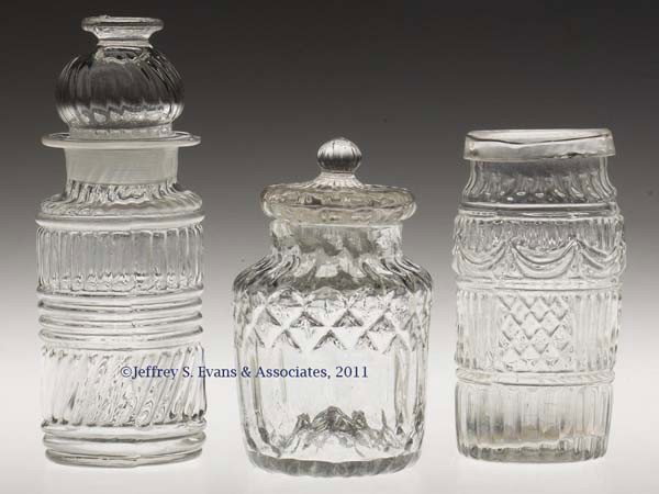 THREE BLOWN-MOLDED CONDIMENT JARS: THREE BLOWN-MOLDED CONDIMENT JARS, colorless, comprising a GI-24 with ribbed stopper, a GII-44 with folded rim, and an unidentified low jar molded with diamonds, prisms and ribs, and with a ribbed sto