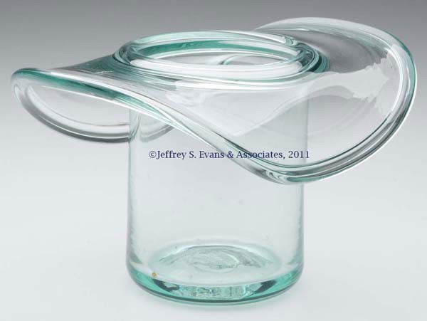 FREE-BLOWN HAT-FORM WHIMSY: FREE-BLOWN HAT-FORM WHIMSY, bottle green, folded inner and outer rim, rough pontil mark. United States. 1880-1920. 4" H, 2 7/8" D base.