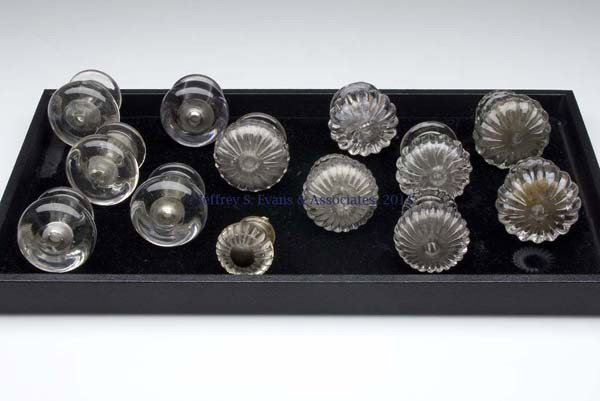 THIRTEEN ASSORTED BLOWN FURNITURE KNOBS: THIRTEEN ASSORTED BLOWN FURNITURE KNOBS, colorless, each of heavy, hollow form, seven molded with ribs, five unpatterned, and one with cut rays on face, one with original metal shank. United States. 1