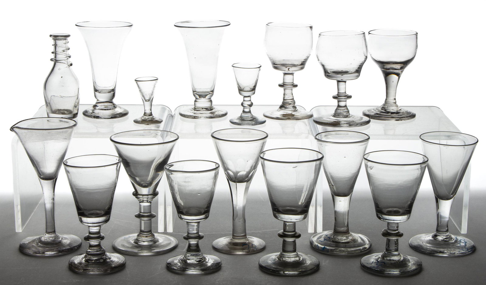 FREE-BLOWN GLASS DRINKING ARTICLES, LOT OF 17: FREE-BLOWN GLASS DRINKING ARTICLES, LOT OF 17, colorless, comprising 12 wines with one having a tooled spout, two jelly glasses, a diminutive decanter, and two toy wines. Various makers. 19th century.