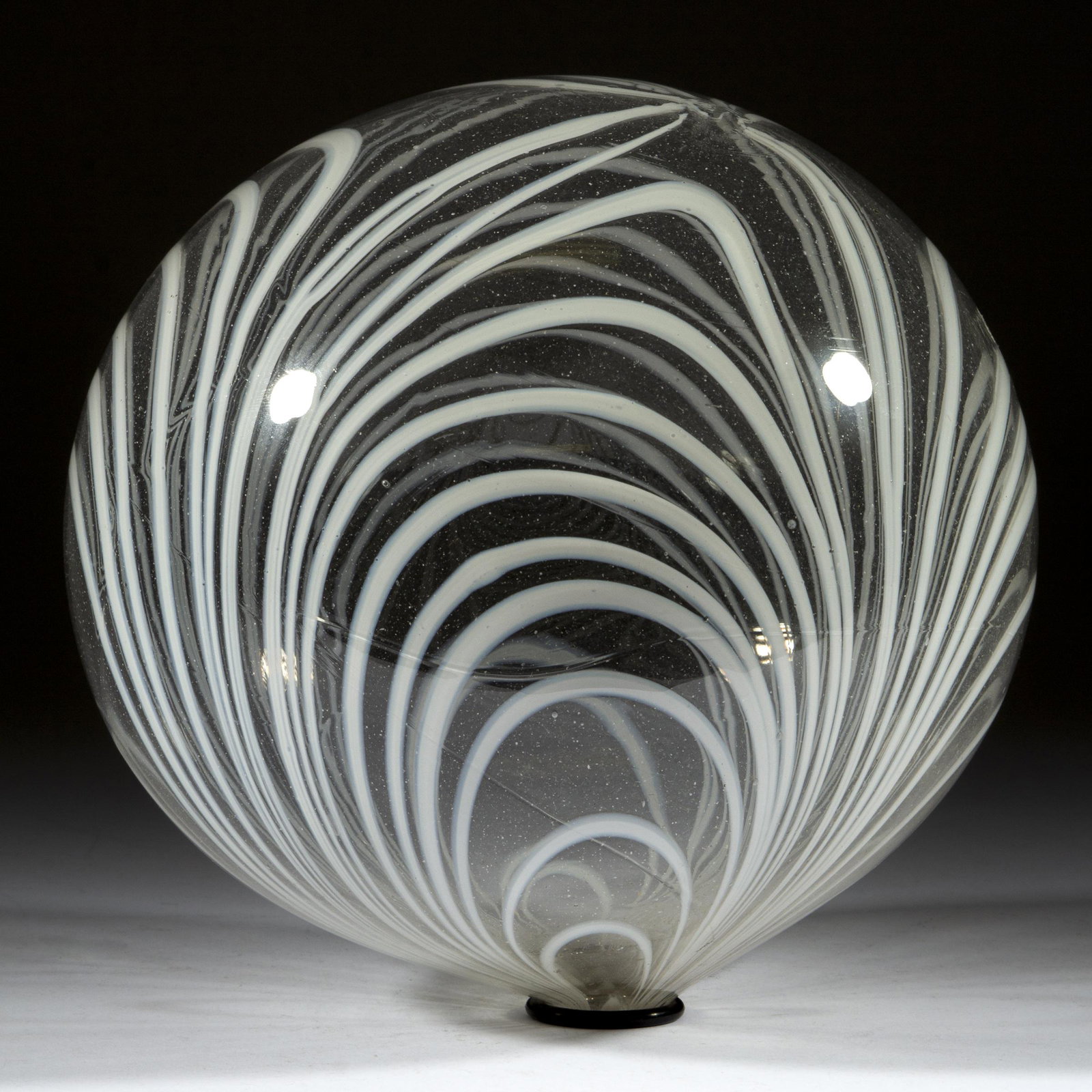 FREE-BLOWN MARBRIE-DECORATED LARGE WITCH BALL: FREE-BLOWN MARBRIE-DECORATED LARGE WITCH BALL, colorless with applied opal loops, rough pontil mark with a 1/2" opening. Boston & Sandwich Glass Co. and others. 1840-1880. 7 1/2" D. Provenance: Glass 