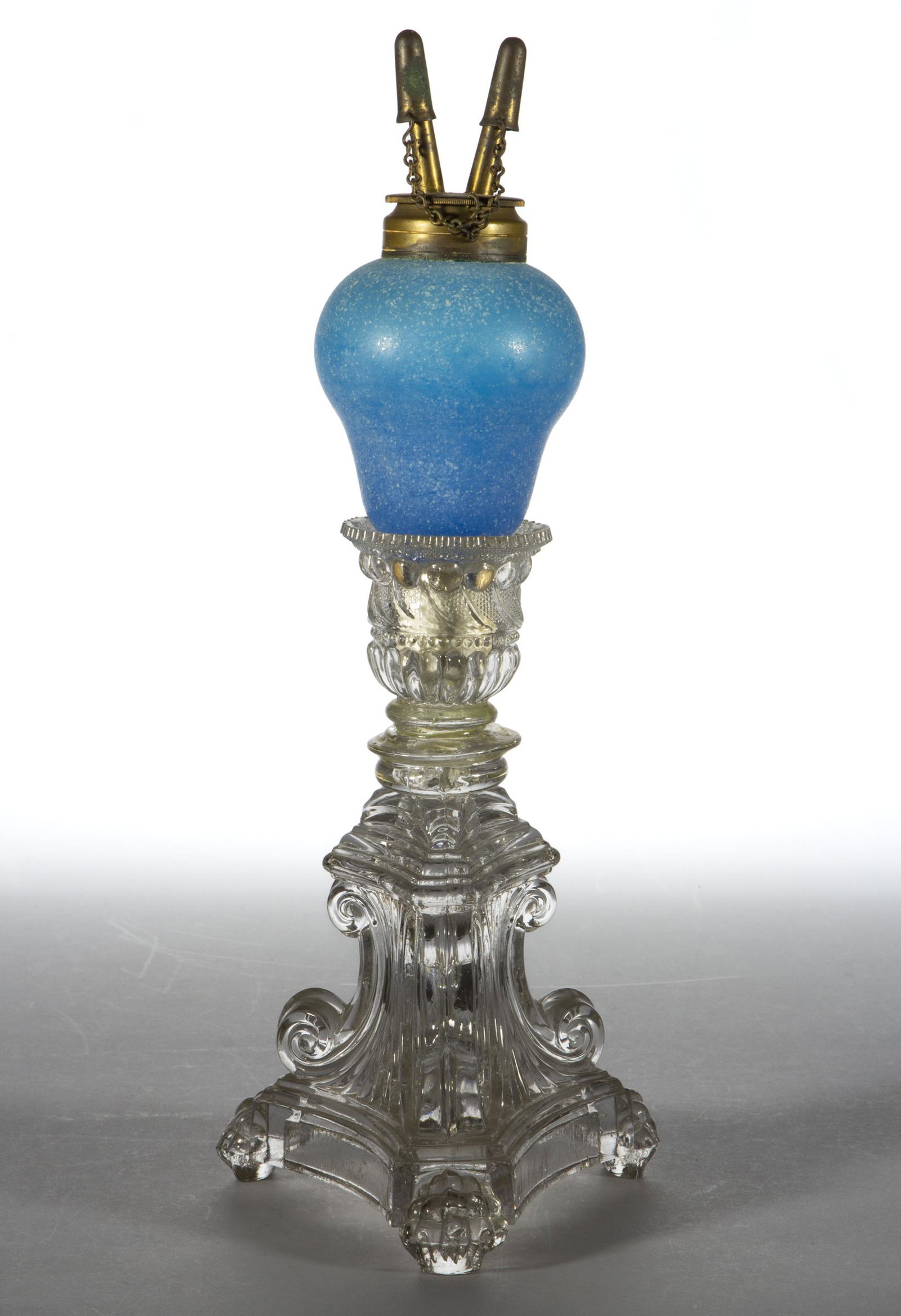 TRANSPARENT BLOWN GLASS KEROSENE PEG LAMP: TRANSPARENT BLOWN GLASS KEROSENE PEG LAMP, translucent starch blue with a sanded surface, pyriform peg font fitted into a colorless lacy C-Scroll candlestick, having a period brass collar. Fitted with