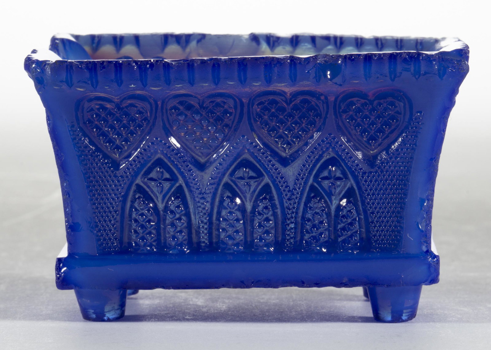 GA-4A GOTHIC ARCH AND HEART PRESSED OPEN SALT: GA-4A GOTHIC ARCH AND HEART PRESSED OPEN SALT, opalescent medium blue with some light blue mottling, even-scallop rim, raised on bucket-like feet. Scarce. Probably Boston & Sandwich Glass Co. 1835-184