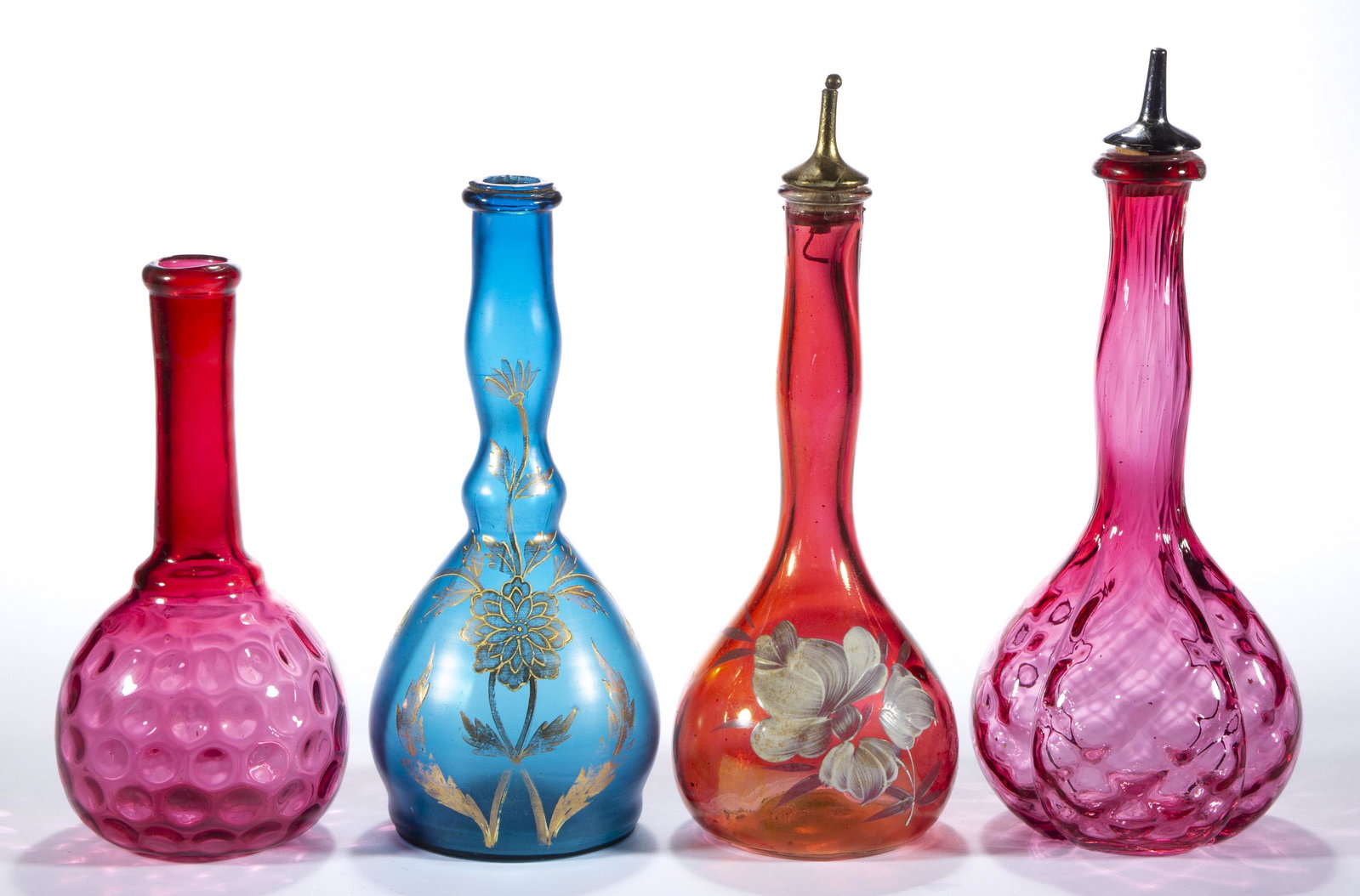 ASSORTED VICTORIAN GLASS BARBER'S / BITTERS BOTTLES, LOT OF THREE,: ASSORTED VICTORIAN GLASS BARBER'S / BITTERS BOTTLES, LOT OF THREE, cranberry, comprising a lobed Diamond-Quilt with a metal spout, a blown-molded example with floral enamel decoration and a period spo