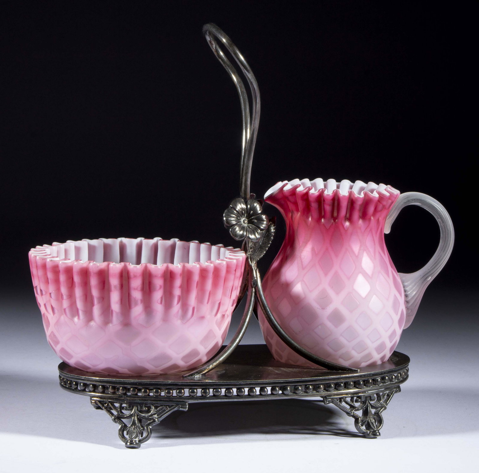 DIAMOND-QUILT AIR-TRAP MOTHER-OF-PEARL CREAM AND SUGAR SET,: DIAMOND-QUILT AIR-TRAP MOTHER-OF-PEARL CREAM AND SUGAR SET, shaded cranberry, comprising a creamer and matching bowl with a ruffled rim, fitted into a quadruple-plate stand marked for "TORONTO S. P. C