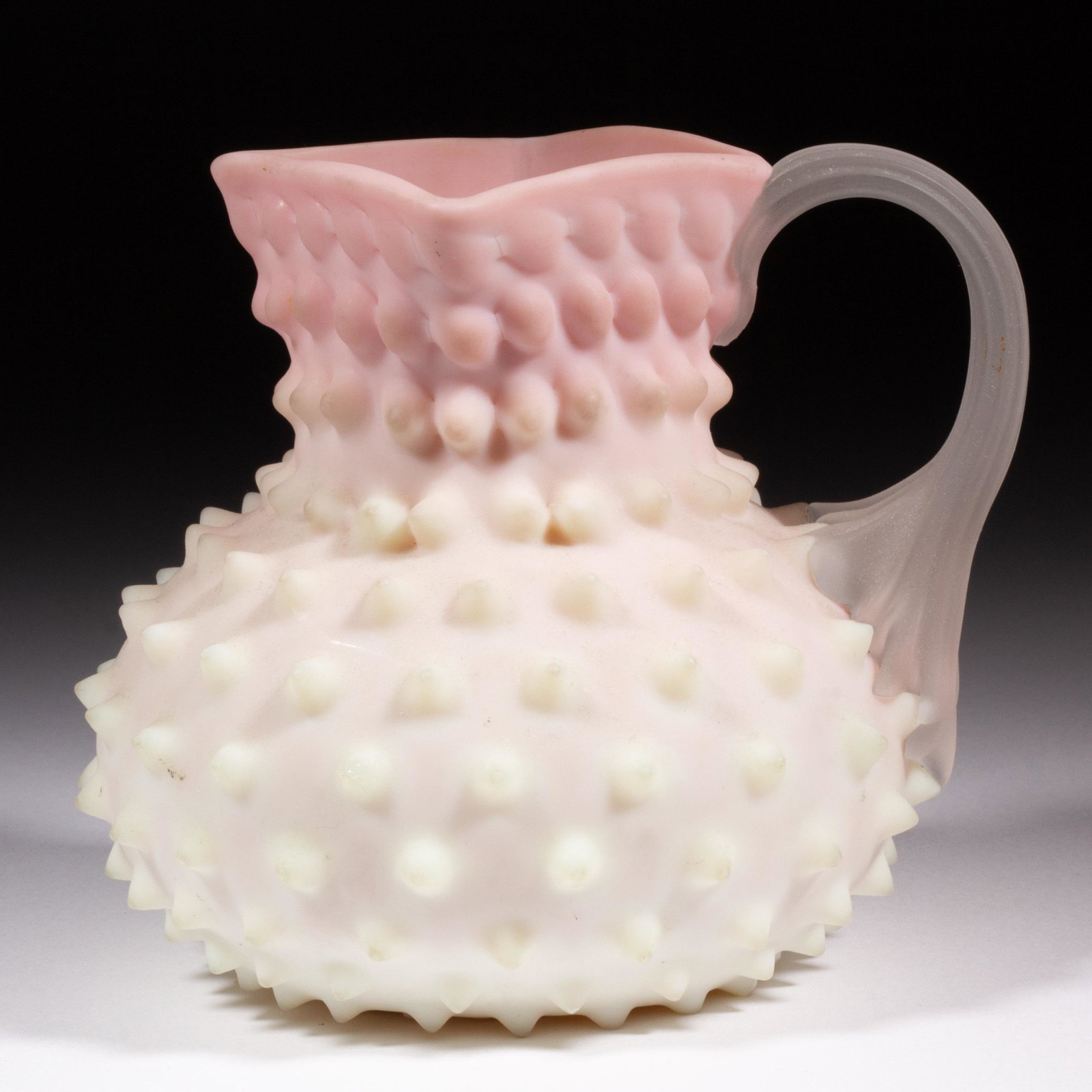 PHOENIX KNOB-OPTIC / HOBNAIL PITCHER,: PHOENIX KNOB-OPTIC / HOBNAIL PITCHER, Burmese with a plush finish, bulbous form with a square rim, applied frosted colorless reeded handle, polished pontil mark. Phoenix Glass Co. 1883-1888. 4 5/8" H.