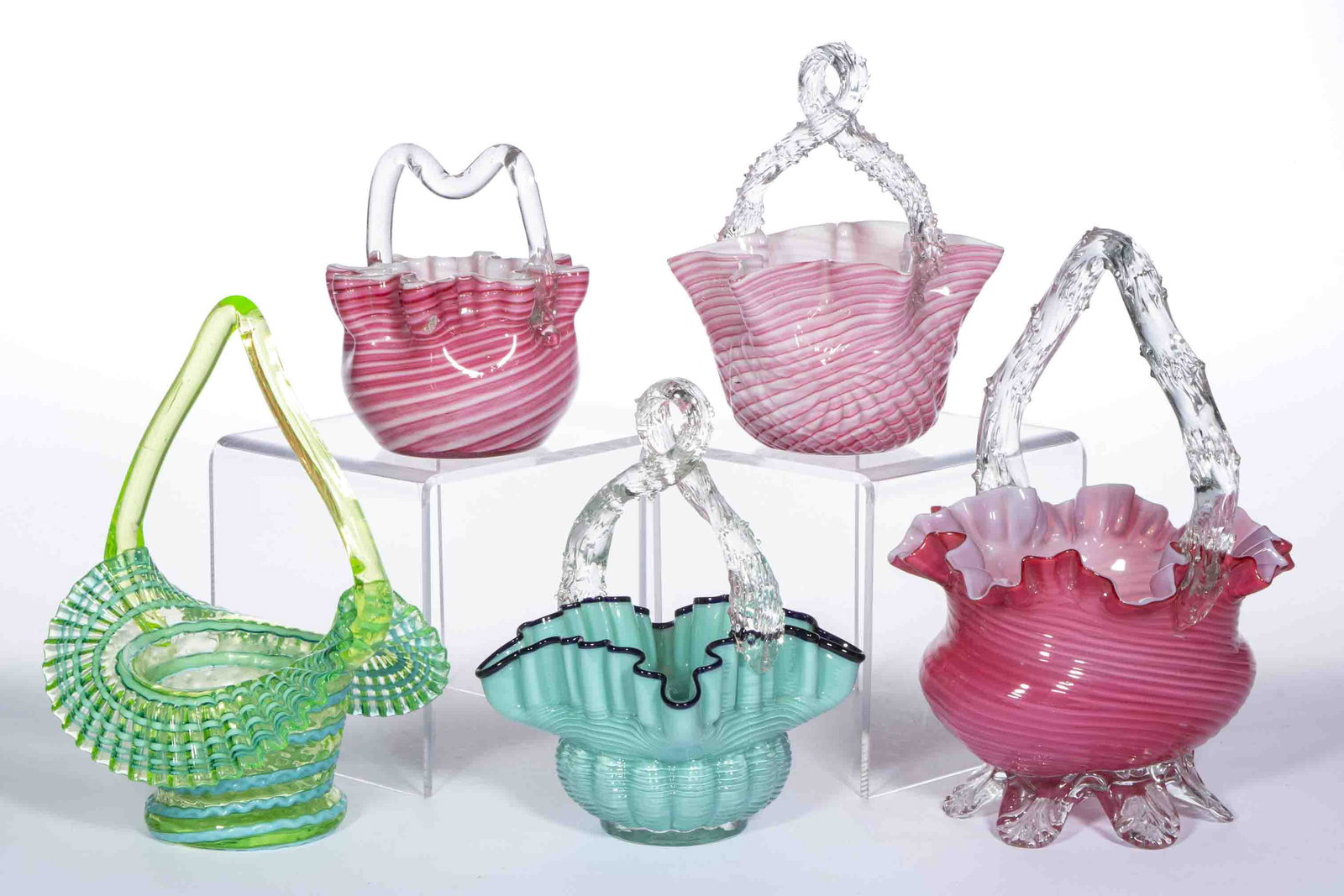 ASSORTED VICTORIAN SWIRL GLASS BASKETS, LOT OF FIVE,: ASSORTED VICTORIAN SWIRL GLASS BASKETS, LOT OF FIVE, various colors, including a Candy Stripe, an Embossed Pinwheel, and a green and opal Swirl, each having an applied basket handle. Various makers. L