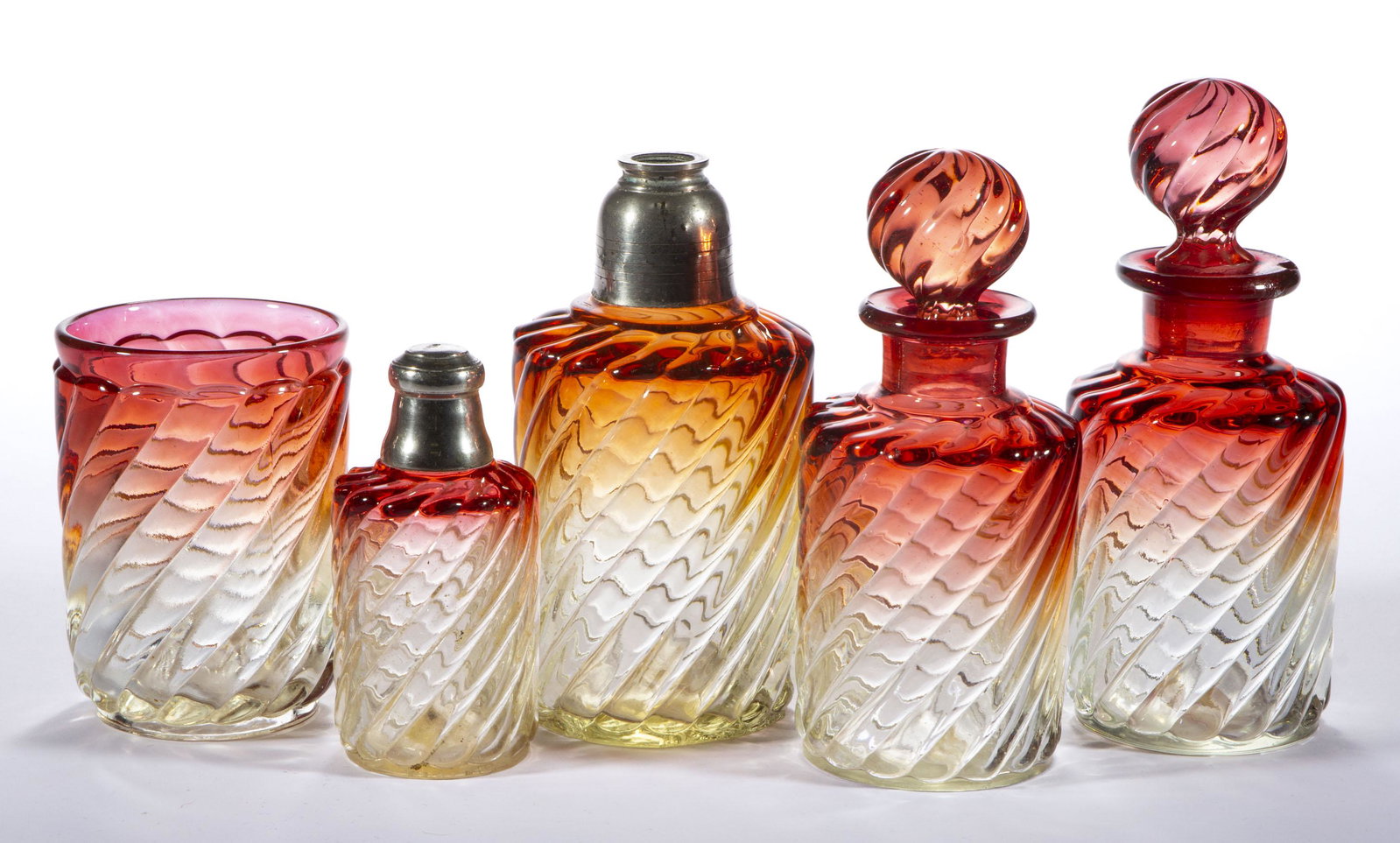 BACCARAT ROSE TIENTE SWIRL DRESSER ARTICLES, LOT OF FIVE,: BACCARAT ROSE TIENTE SWIRL DRESSER ARTICLES, LOT OF FIVE, comprising two cologne bottles with matching stoppers, an atomizer base with metal collar but lacking head and cord, a tumbler, and a water sp