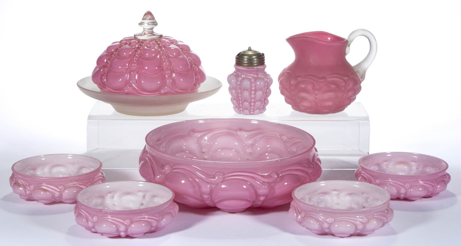 GUTTATE TABLE ARTICLES, LOT OF EIGHT,: GUTTATE TABLE ARTICLES, LOT OF EIGHT, cased pink, including a covered butter dish, creamer, and a five-piece berry set. Consolidated Lamp & Glass Co. Circa 1894. 1 1/2" to 5 1/4" HOA. Master berry: 8"