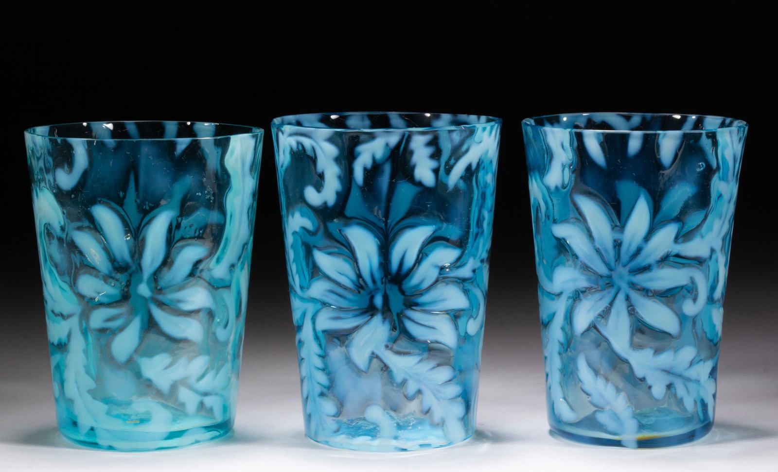POINSETTIA TUMBLERS, LOT OF THREE,: POINSETTIA TUMBLERS, LOT OF THREE, blue opalescent, each having a factory-polished rim. H Northwood Co. Circa 1903. 4" H. Literature: Parallels Heacock/Elmore - Opalescent Glass From A to Z, p. 128, f