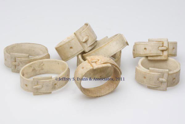 SET OF EIGHT SCRIMSHAW BONE / IVORY NAPKIN RINGS: SET OF EIGHT SCRIMSHAW IVORY NAPKIN RINGS, each in the form of a belt with buckle. 19th century. Average 1/2" H, 1 1/2" D.