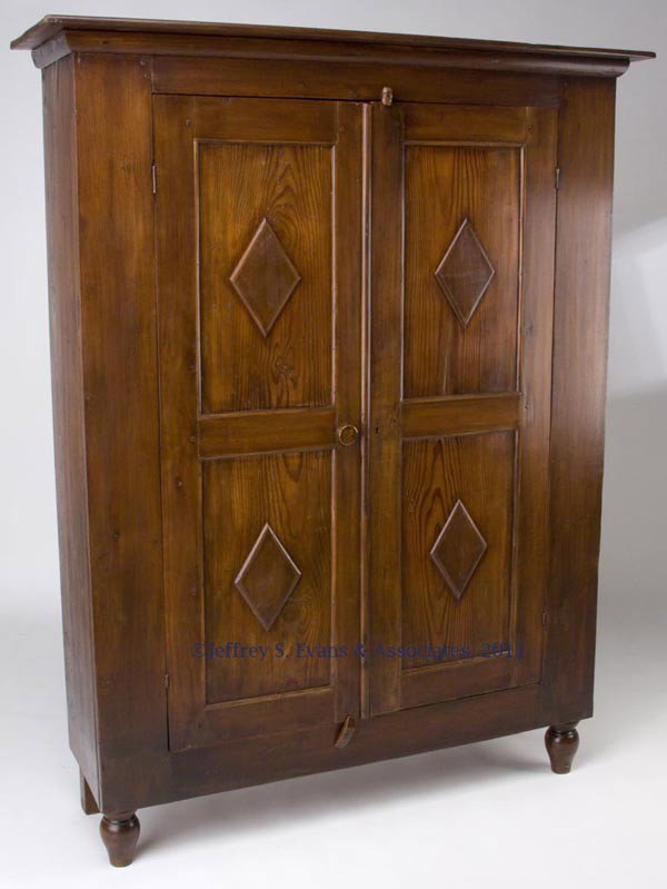 MID-ATLANTIC VERNACULAR CUPBOARD: MID-ATLANTIC VERNACULAR CUPBOARD, poplar and yellow pine, simple cornice above two paneled doors, each with two applied diamond-shape ornaments and concealing two interior shelves, raised on turned fr
