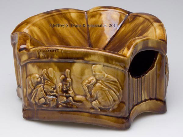 BENNETT ROCKINGHAM-GLAZE POTTERY SPITTOON: BENNETT ROCKINGHAM-GLAZE POTTERY SPITTOON, mottled brown, having three short sides with vertical ribs, and three longer sides, with two different molded scenes of monkeys partying, impressed "R. BENNE
