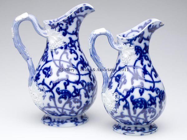 ENGLISH STAFFORDSHIRE BRUSH-STROKE FLOW BLUE PITCH: ENGLISH STAFFORDSHIRE BRUSH-STROKE FLOW BLUE PITCHERS, LOT OF TWO MATCHING, possibly Blue Bell by the Swansea Pottery, Wales, each with an intertwined handle decorated with two molded leaves, grapes,