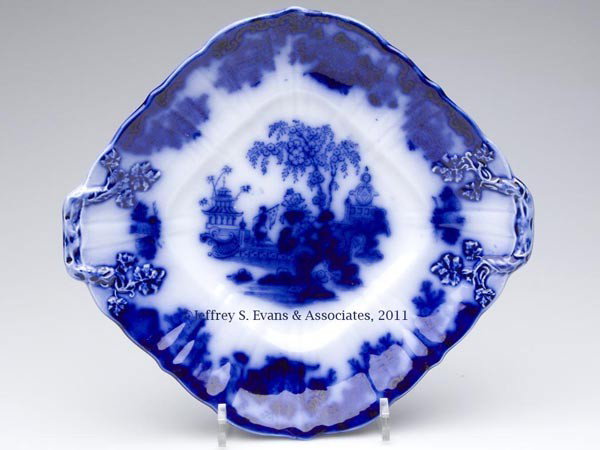 ENGLISH STAFFORDSHIRE TRANSFERWARE FLOW BLUE SERVI: ENGLISH STAFFORDSHIRE TRANSFERWARE FLOW BLUE SERVING PLATE, diamond shape with closed branch handles on opposite corners, base with trademark bearing the name "SCINDE". John & George Alcock, Cobridge,