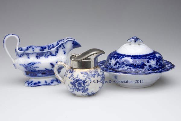 ENGLISH STAFFORDSHIRE AND AMERICAN TRANSFERWARE FL: ENGLISH STAFFORDSHIRE AND AMERICAN TRANSFERWARE FLOW BLUE TABLE ARTICLES, LOT OF THREE, comprising a gravy boat, marked under base "CHANTILLY", maker unidentified; a three-piece butter dish, trademark