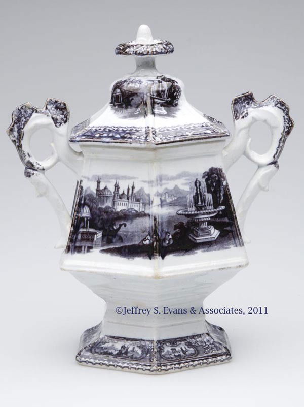 STAFFORDSHIRE TRANSFERWARE PEDESTALLED SUGAR BOWL: STAFFORDSHIRE TRANSFERWARE PEDESTALLED SUGAR BOWL, mulberry on white, Medina pattern by J. Furnival, hexagonal form with ring and bracket Cockscomb handles, flori-form finial, unmarked. England. Mid 1